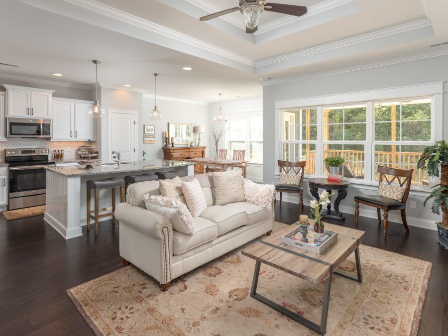 A living room with a couch , coffee table , chairs and a ceiling fan.