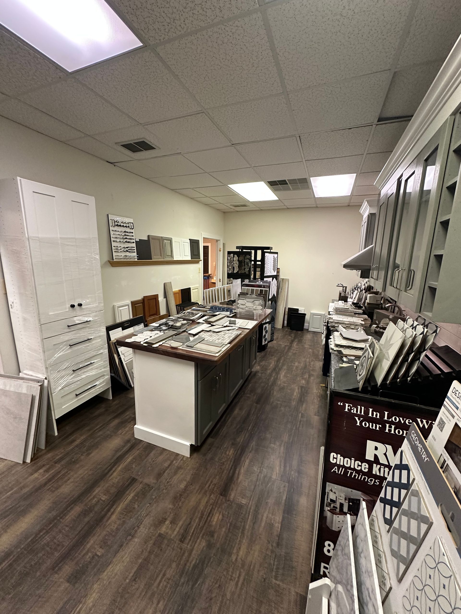 Tile showroom interior with various tile samples, wood flooring, and white cabinetry.