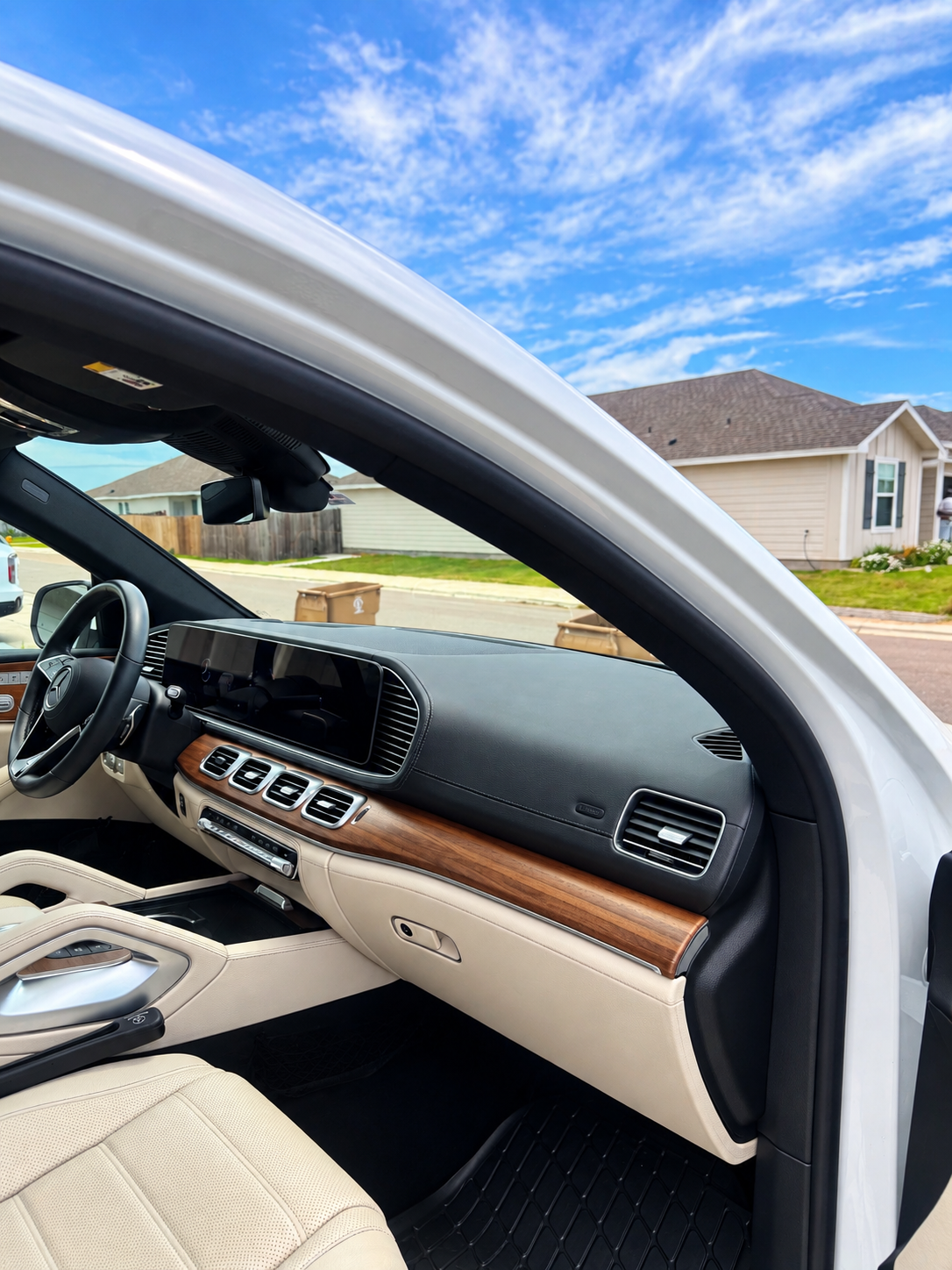 Open truck door showing black leather interior and dashboard under a bright blue sky
