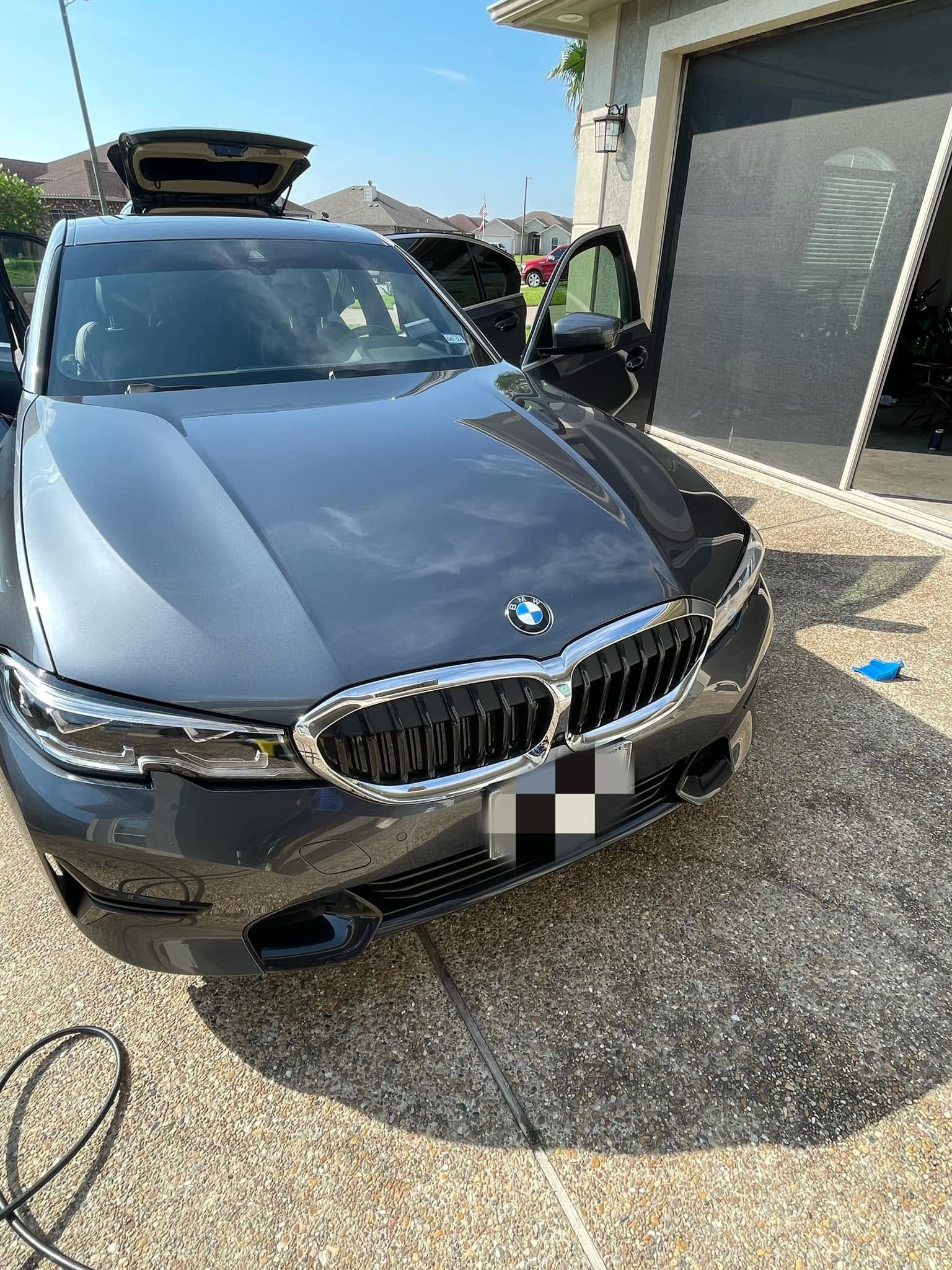 Gray BMW sedan parked outside a building, with a person visible near the driver door.