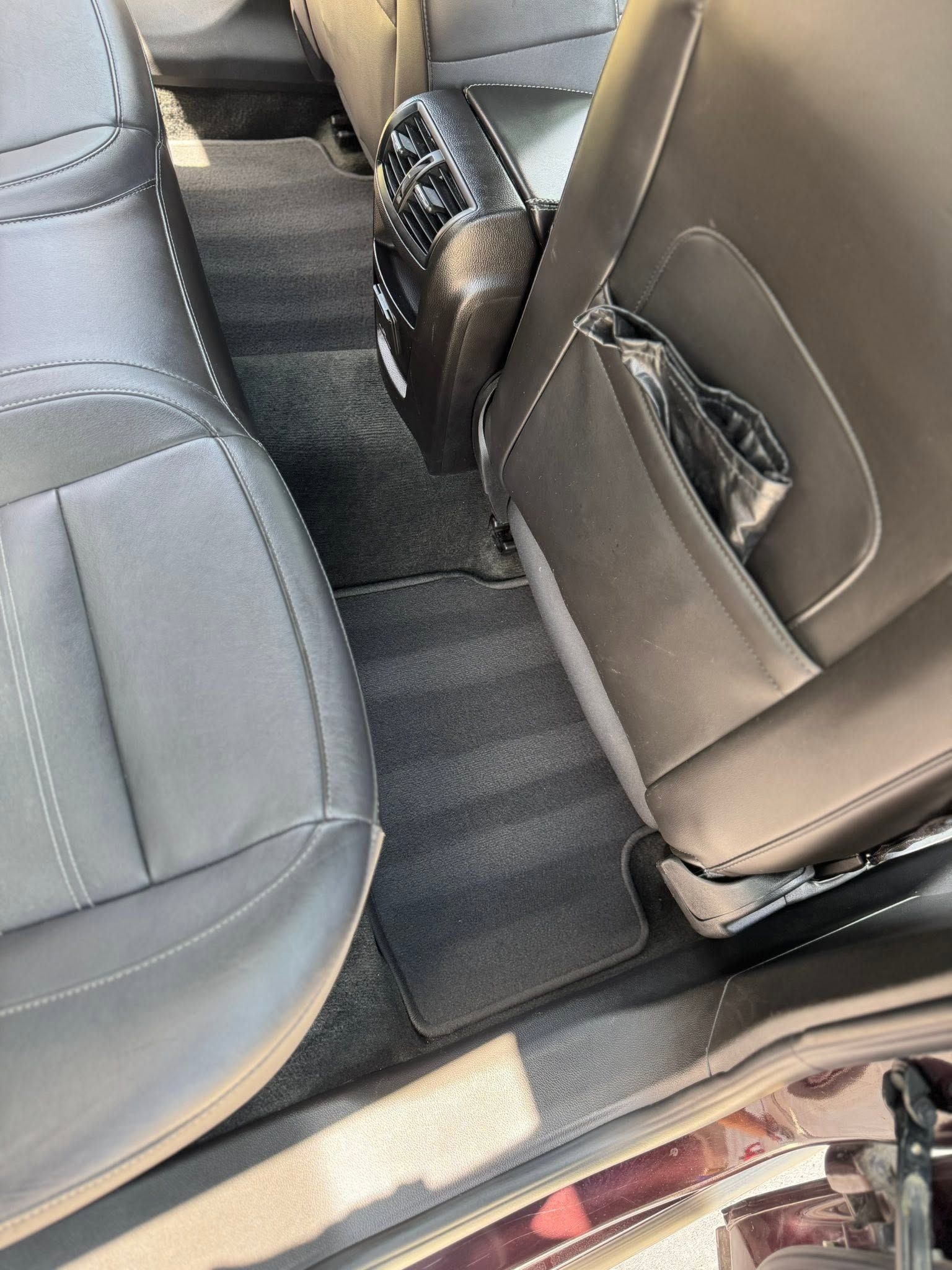 Car interior with two gray seats and a small black fan on the rear floor mat