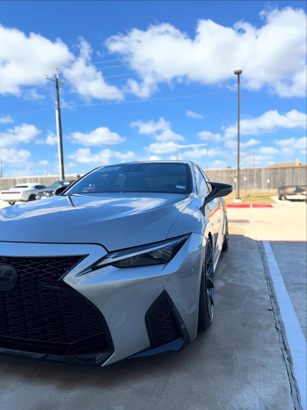 White sports car parked in a lot under a bright blue sky