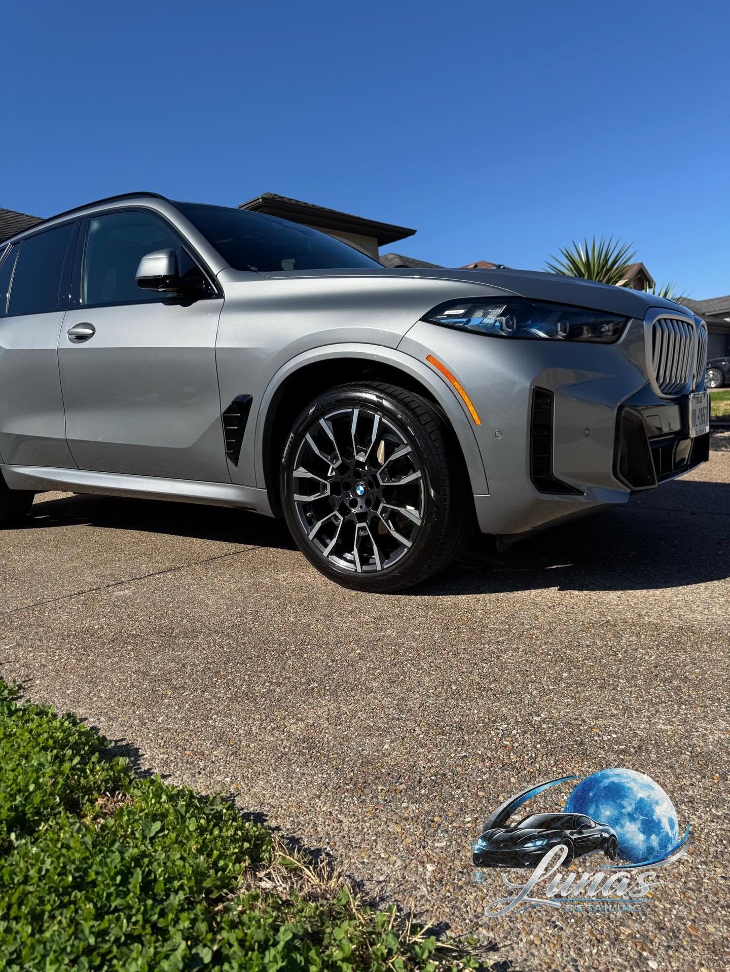 Silver SUV parked on a driveway with a blue helmet on the grass in front of it.