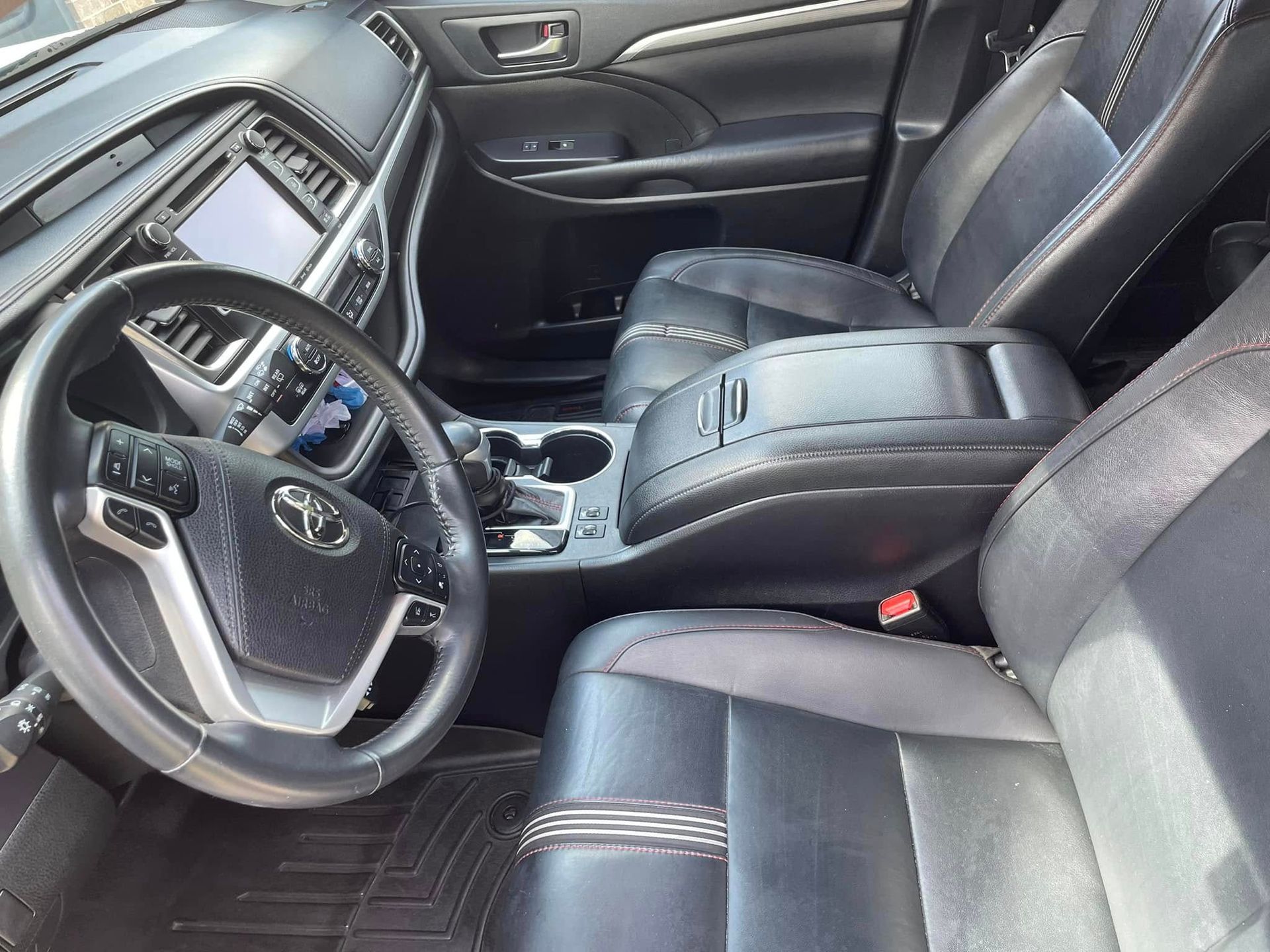 Black leather Toyota car interior with steering wheel, center console, and front seats