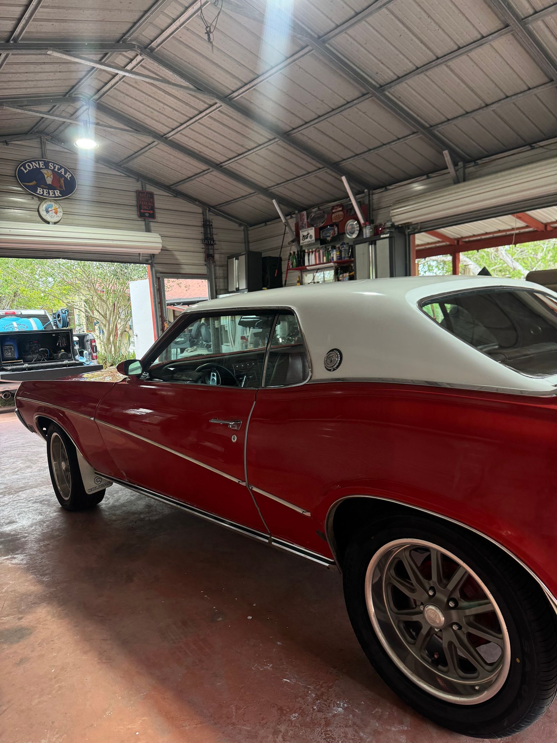 Red and white classic car parked inside a garage with the door open.