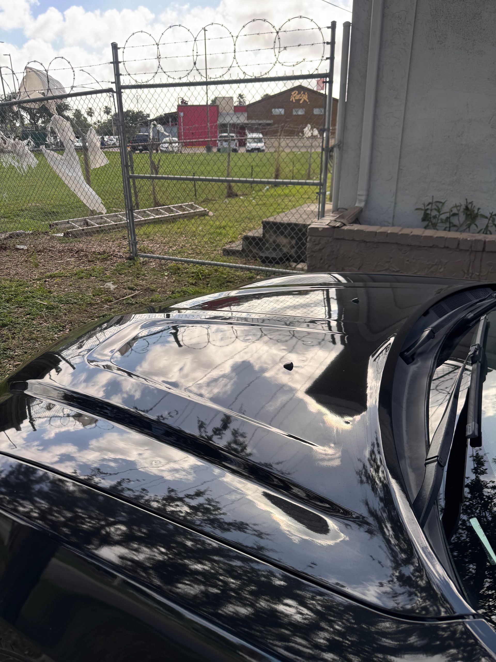 Person washing a black car with soap foam in a driveway
