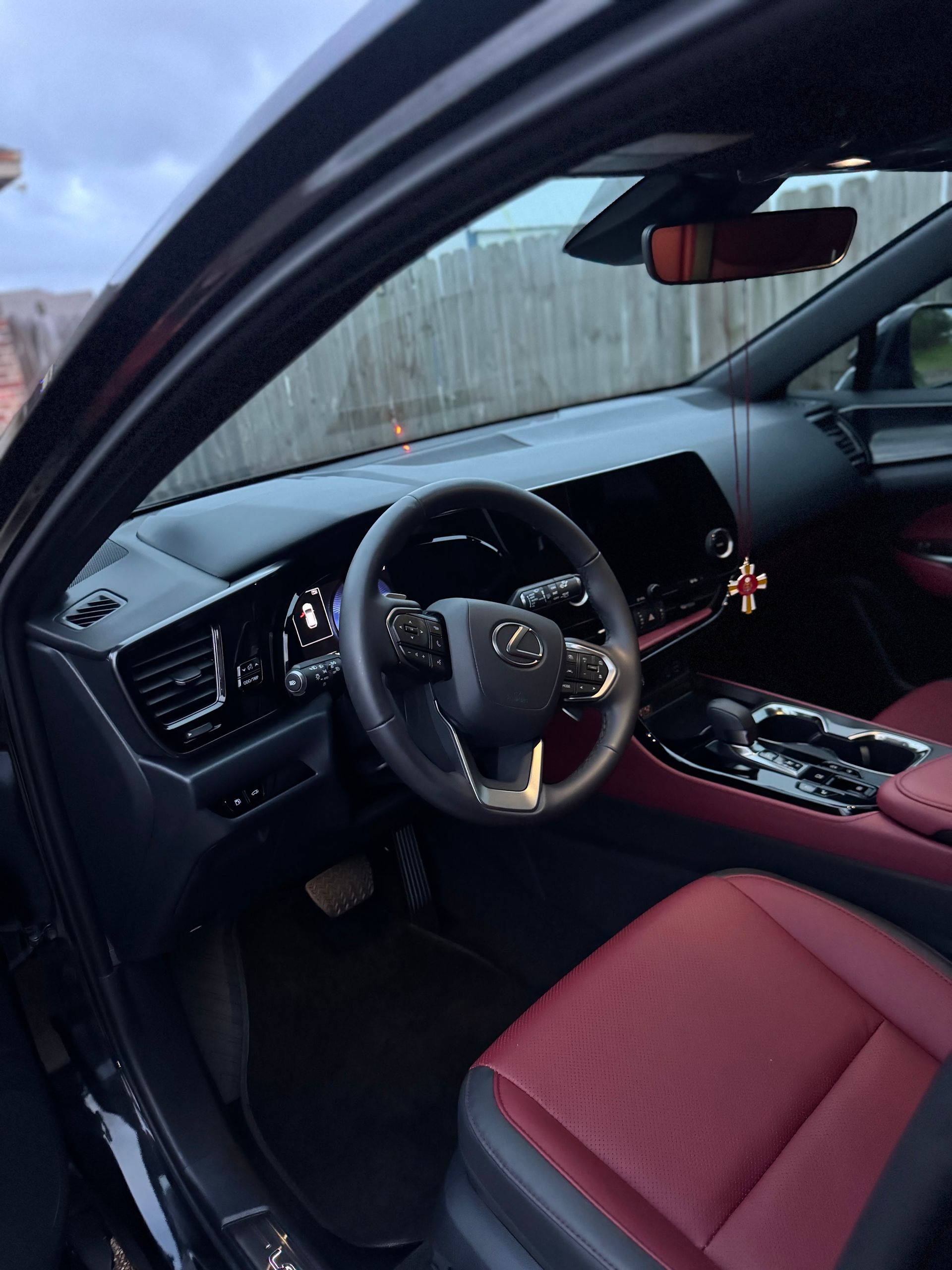 Car interior with black dashboard and red seats, viewed from the driver’s side door.