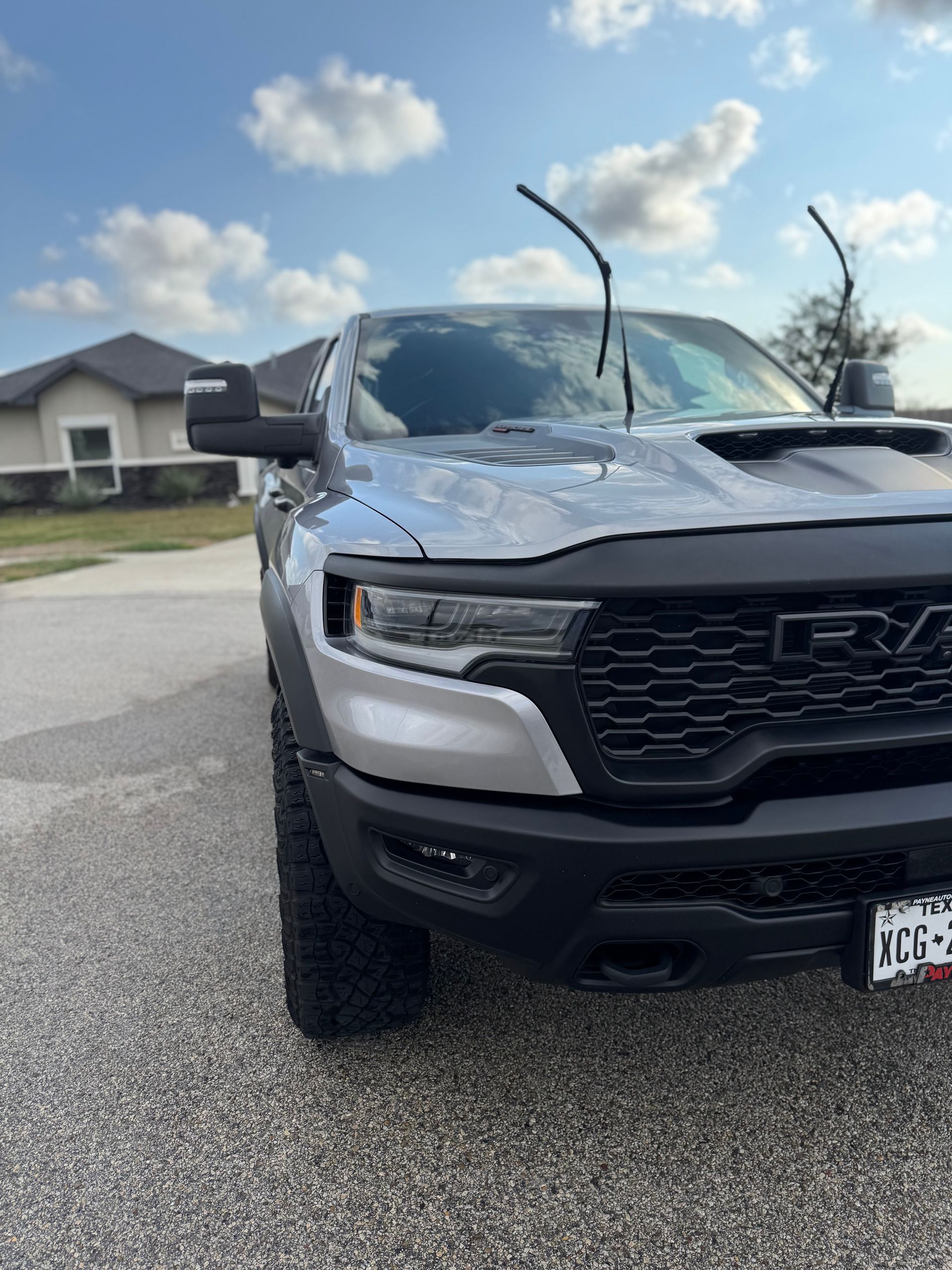 Gray pickup truck parked on a suburban street with wipers raised and hood scoop visible