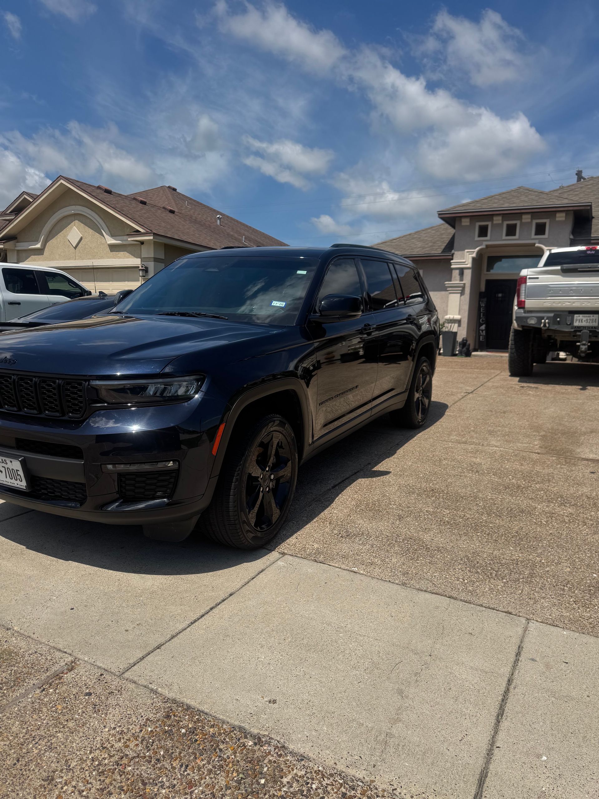Black SUV parked in a suburban driveway under a partly cloudy sky.
