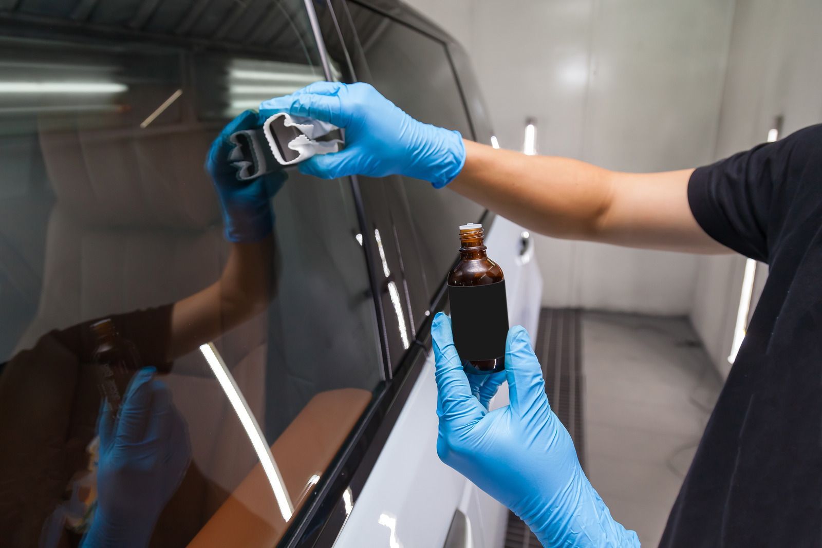 Person polishing a silver car headlight with a blue microfiber cloth and spray bottle