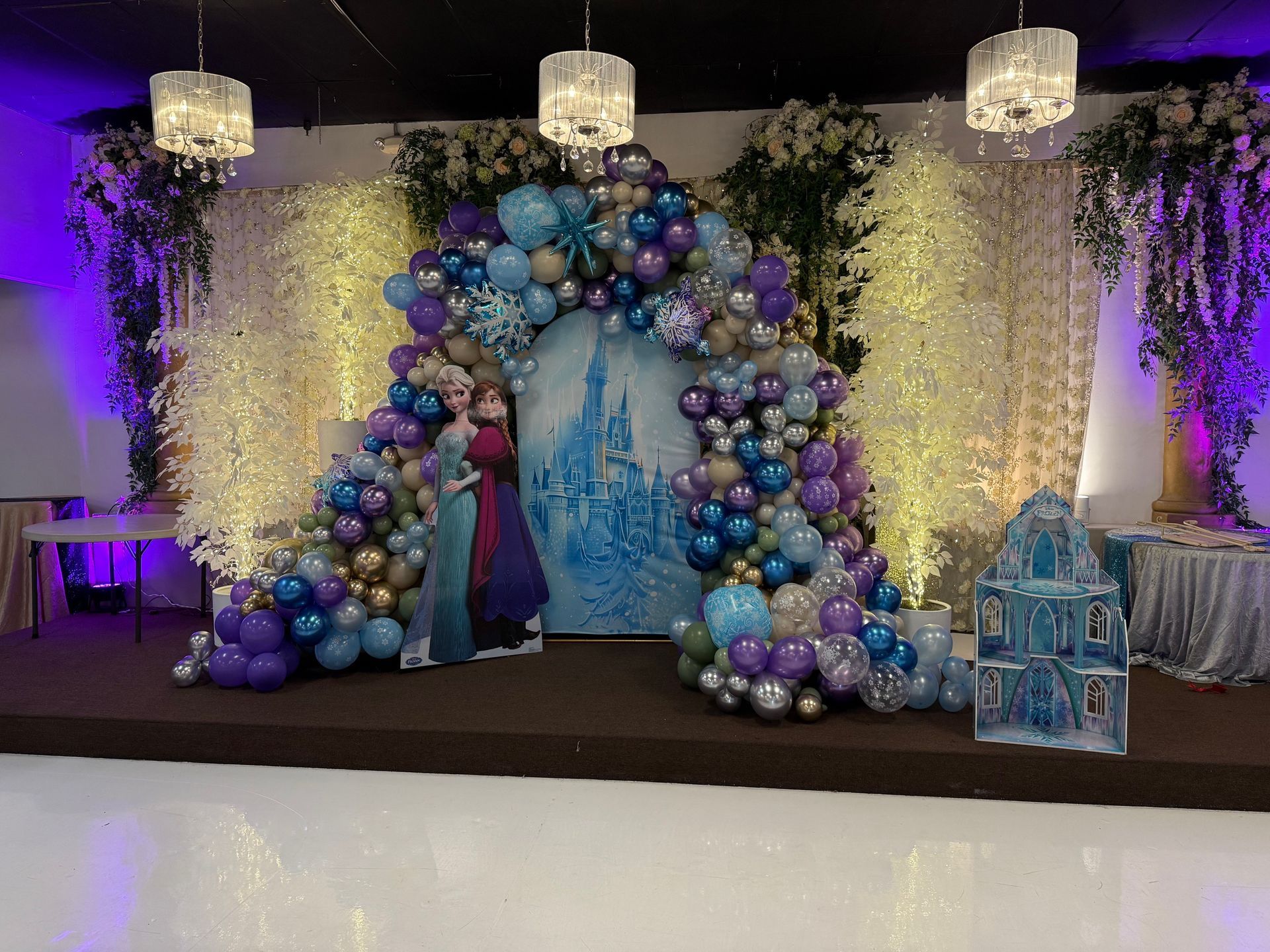 Decorative white tree centerpiece in a dim lounge with draped curtains and black leather chairs