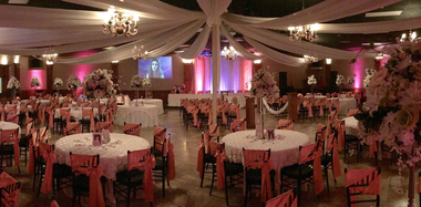 Champagne glass and small cocktail on a table at a softly lit event with purple décor