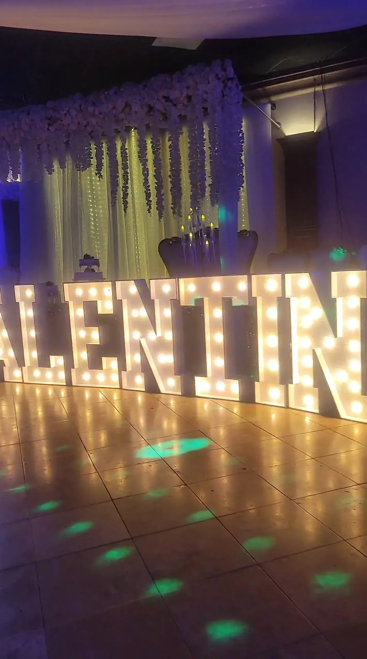 Large illuminated “VALENTINE” sign with warm lights at a decorated indoor event backdrop