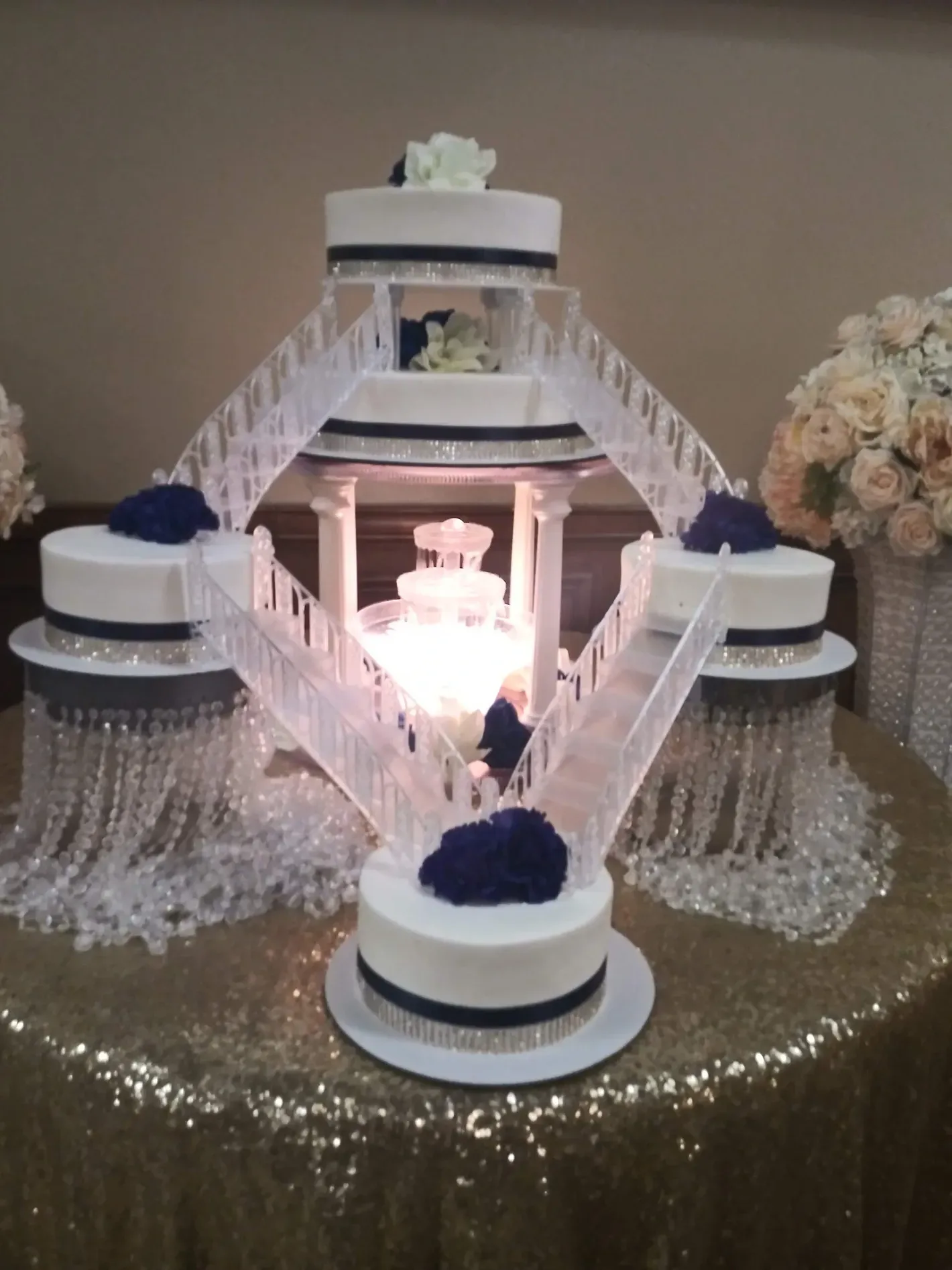 White tiered decorative cake stand with crystal fringe and lit candles on a table centerpiece