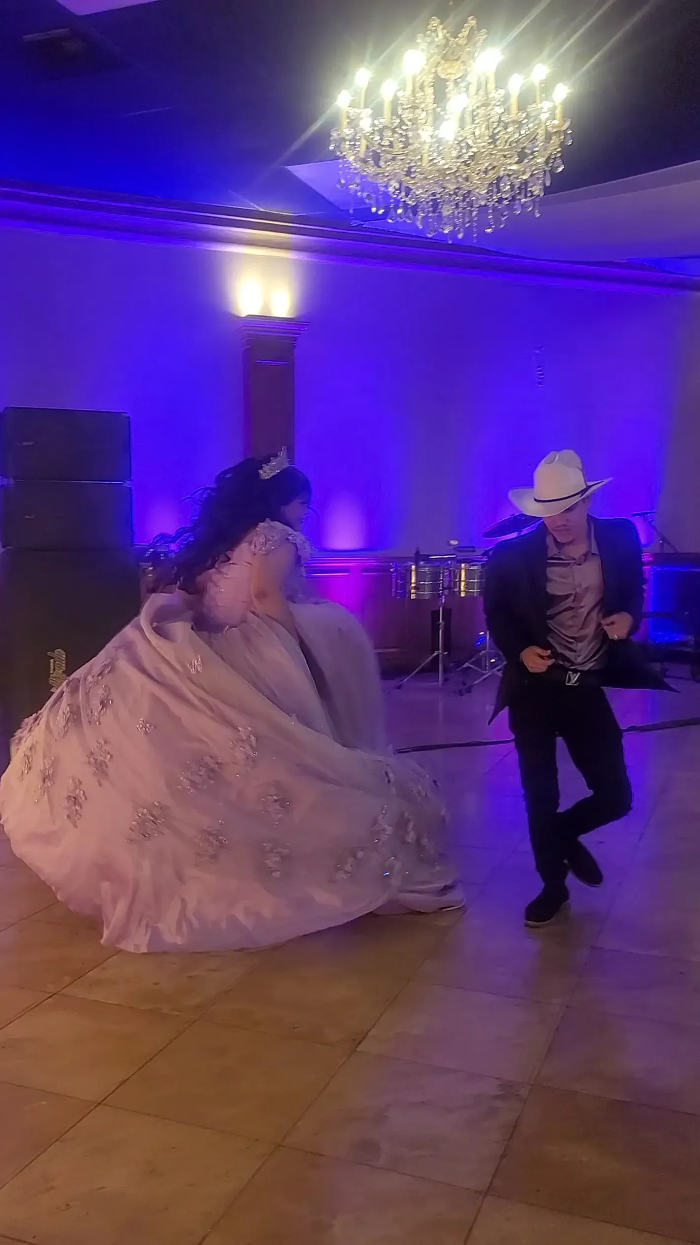 Couple dancing in a purple-lit ballroom with a chandelier overhead