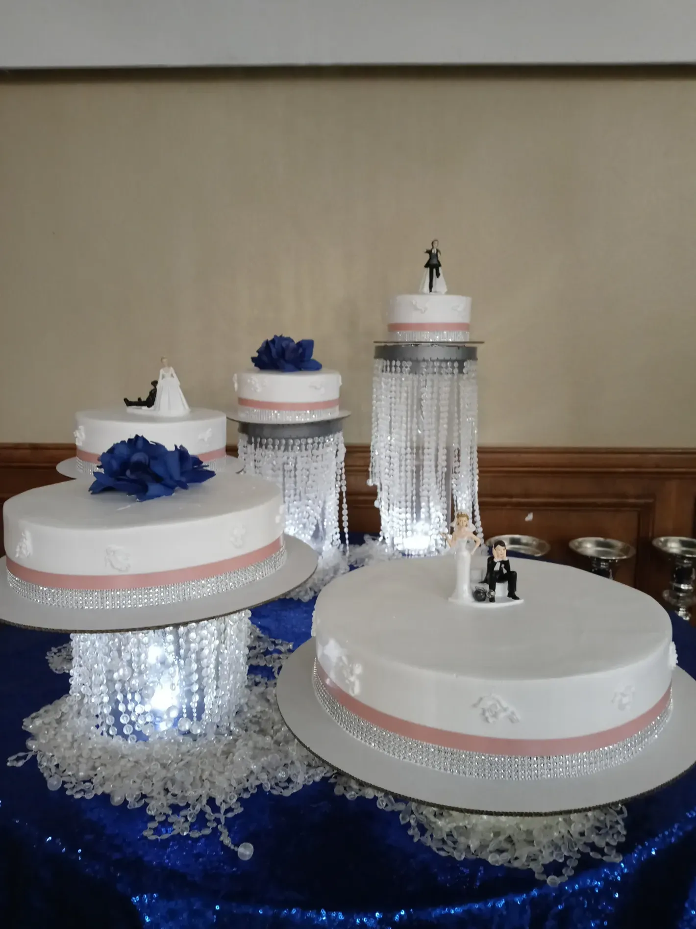 Decorative white display drums and a tall silver column on a blue cloth backdrop