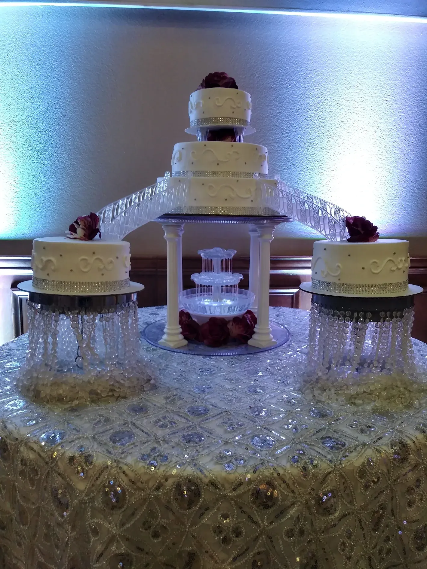 Silver fountain centerpiece with cascading water, lit from behind, decorated with red accents and crystal-like bases