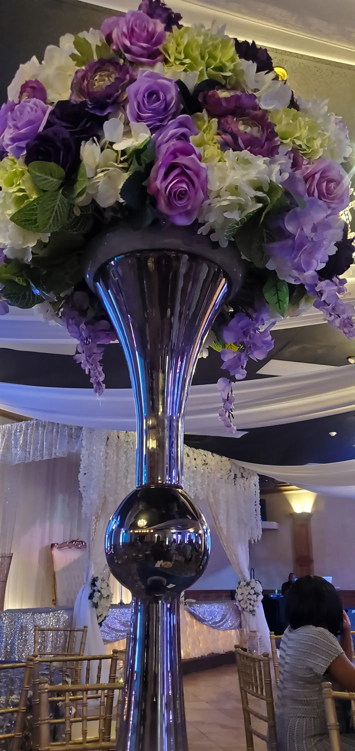 Purple and white floral centerpiece on a mirrored vase at a decorated banquet table