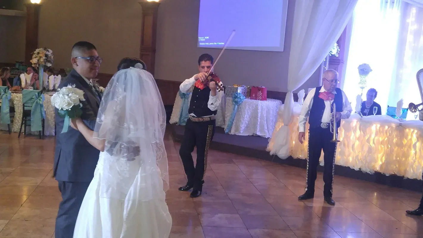 Bride and groom dancing at a wedding reception while musicians perform nearby
