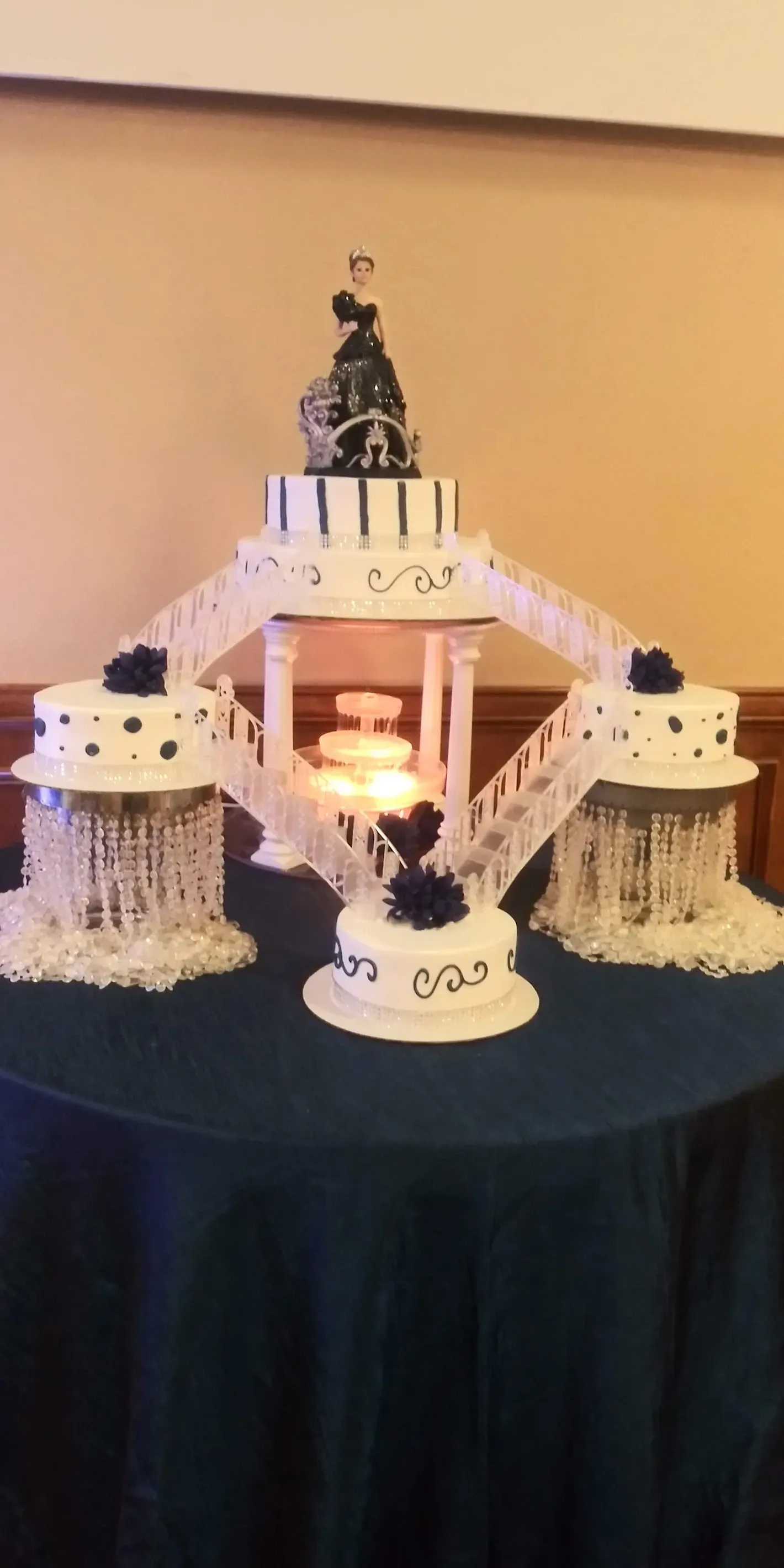 Elegant white tiered cake with black topper and lace-like trim on a dark tablecloth at a formal event
