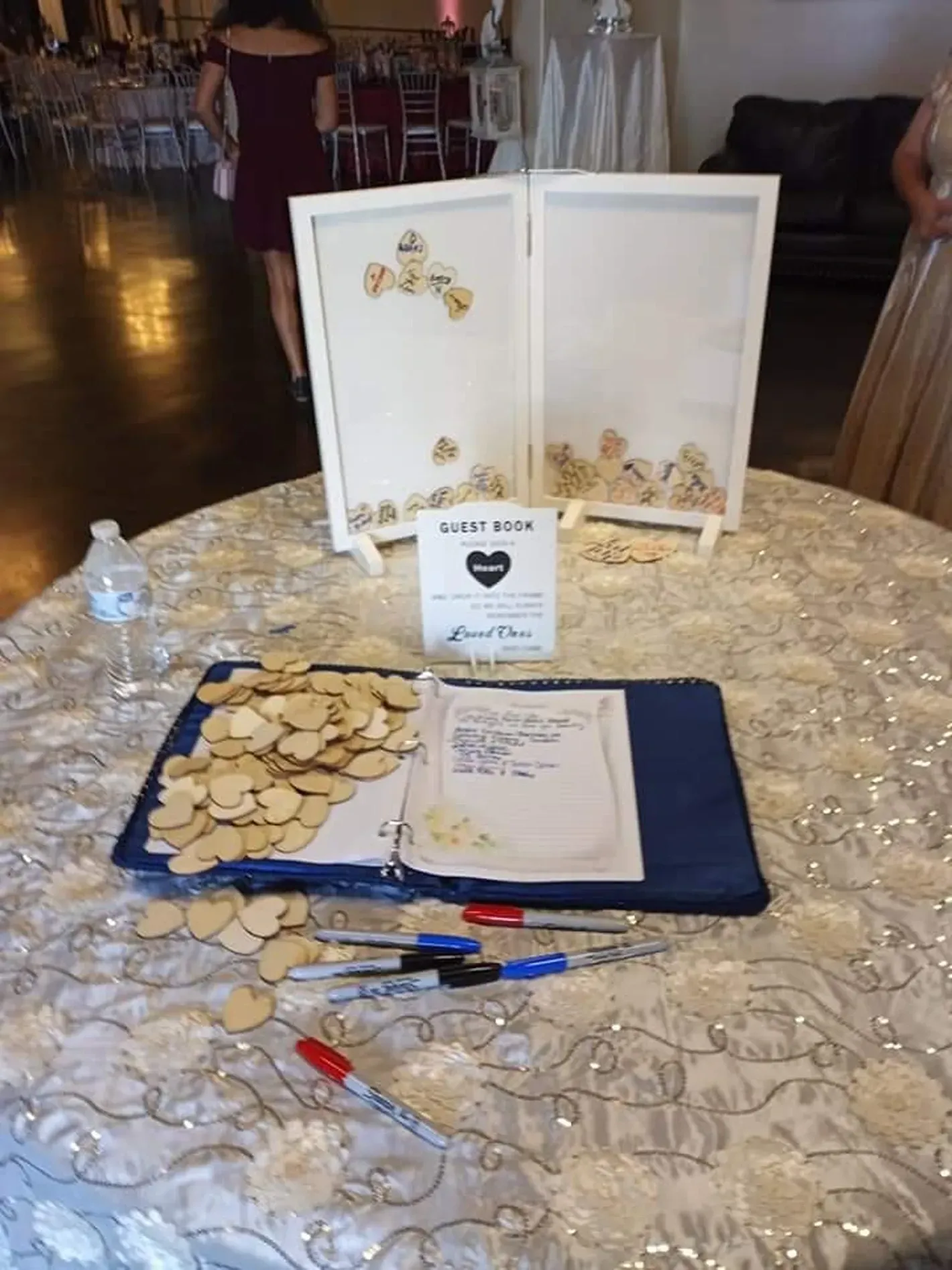 Donation table with sign, decorated cards, pens, and a blue tray of coins on a glittery round table