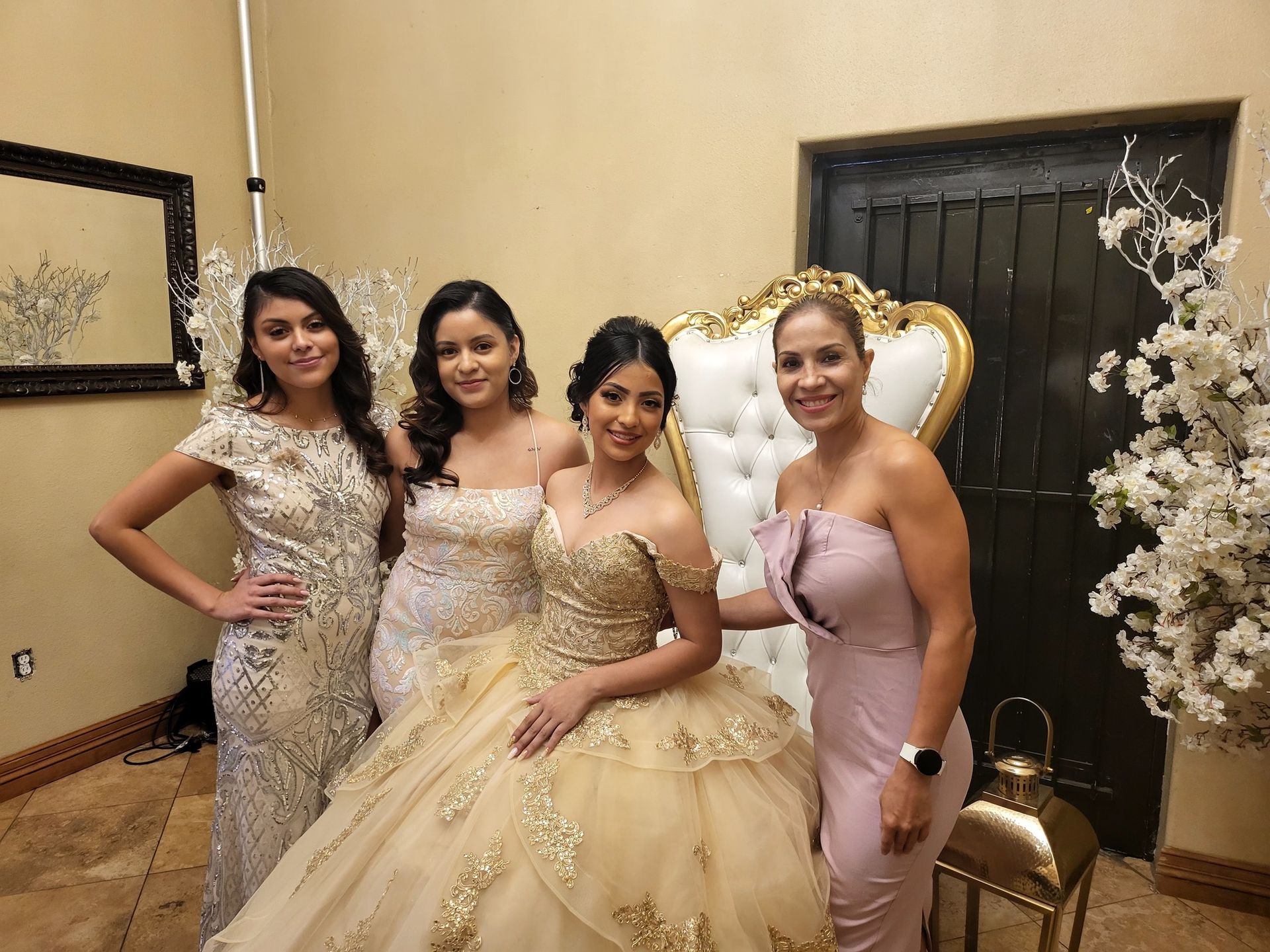 Four women in elegant gowns posing indoors at a formal event