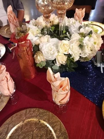 Elegant table setting with white roses, folded peach napkins, and red and navy tablecloths