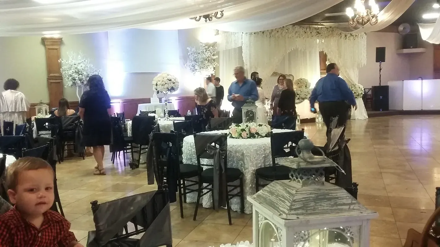 Banquet hall with guests mingling around decorated tables and a child in the foreground