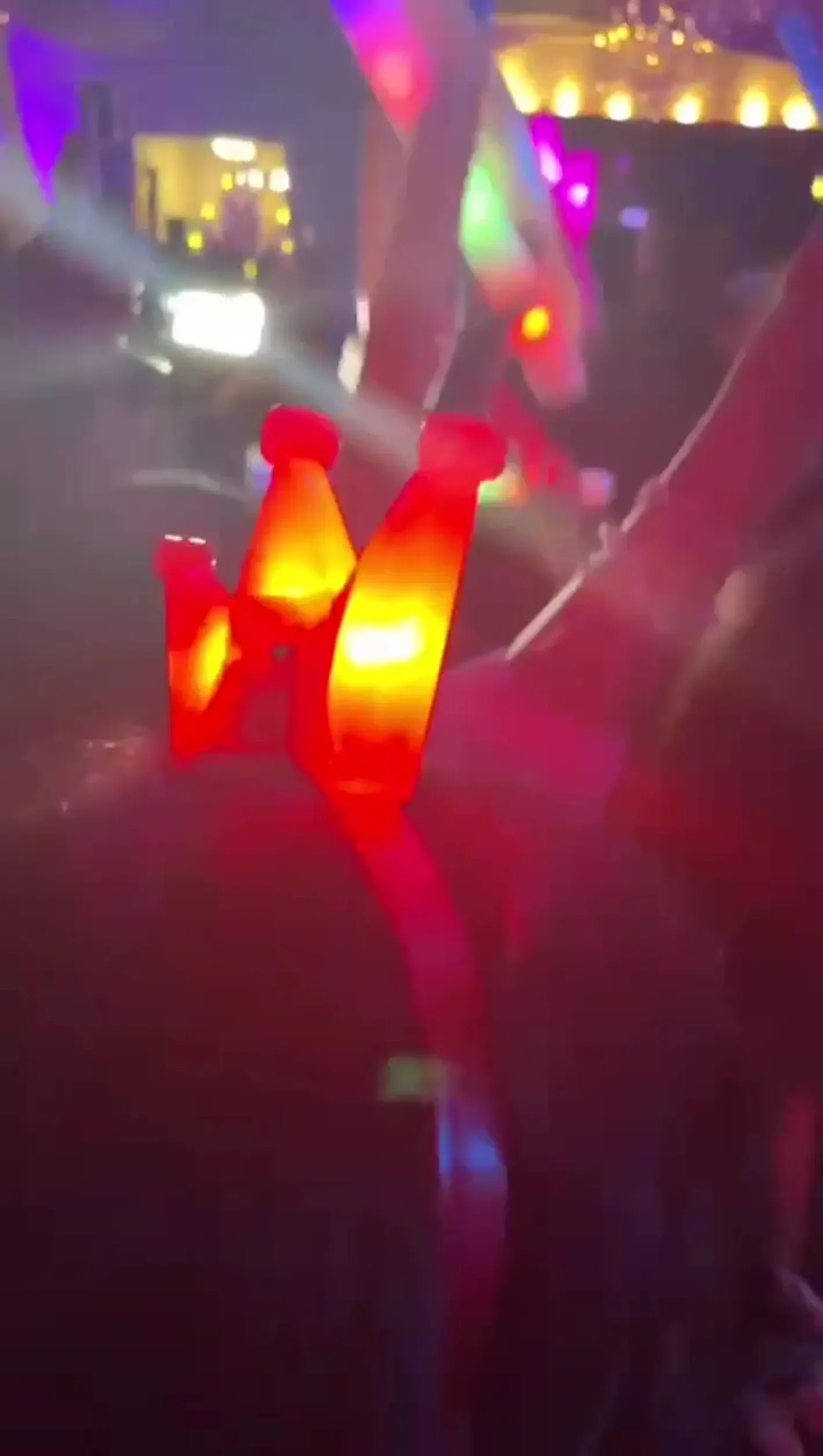 Glow sticks glowing red and yellow at a dim, colorful party scene