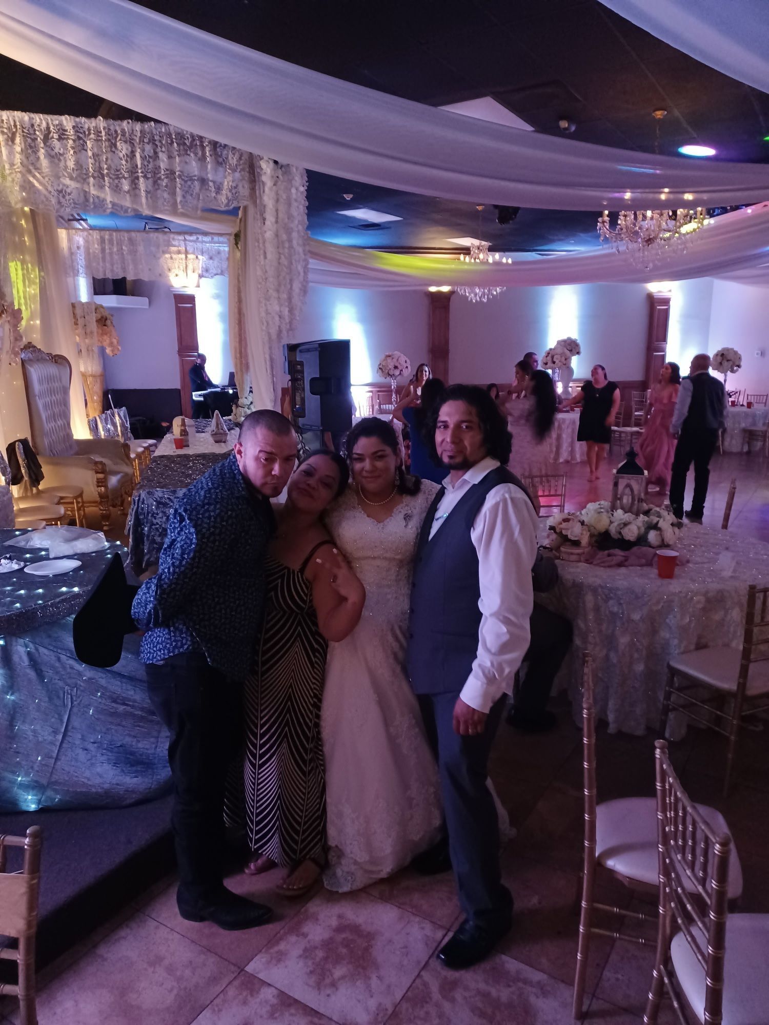 Three people pose smiling at a decorated indoor event with purple lighting and draped ceilings.