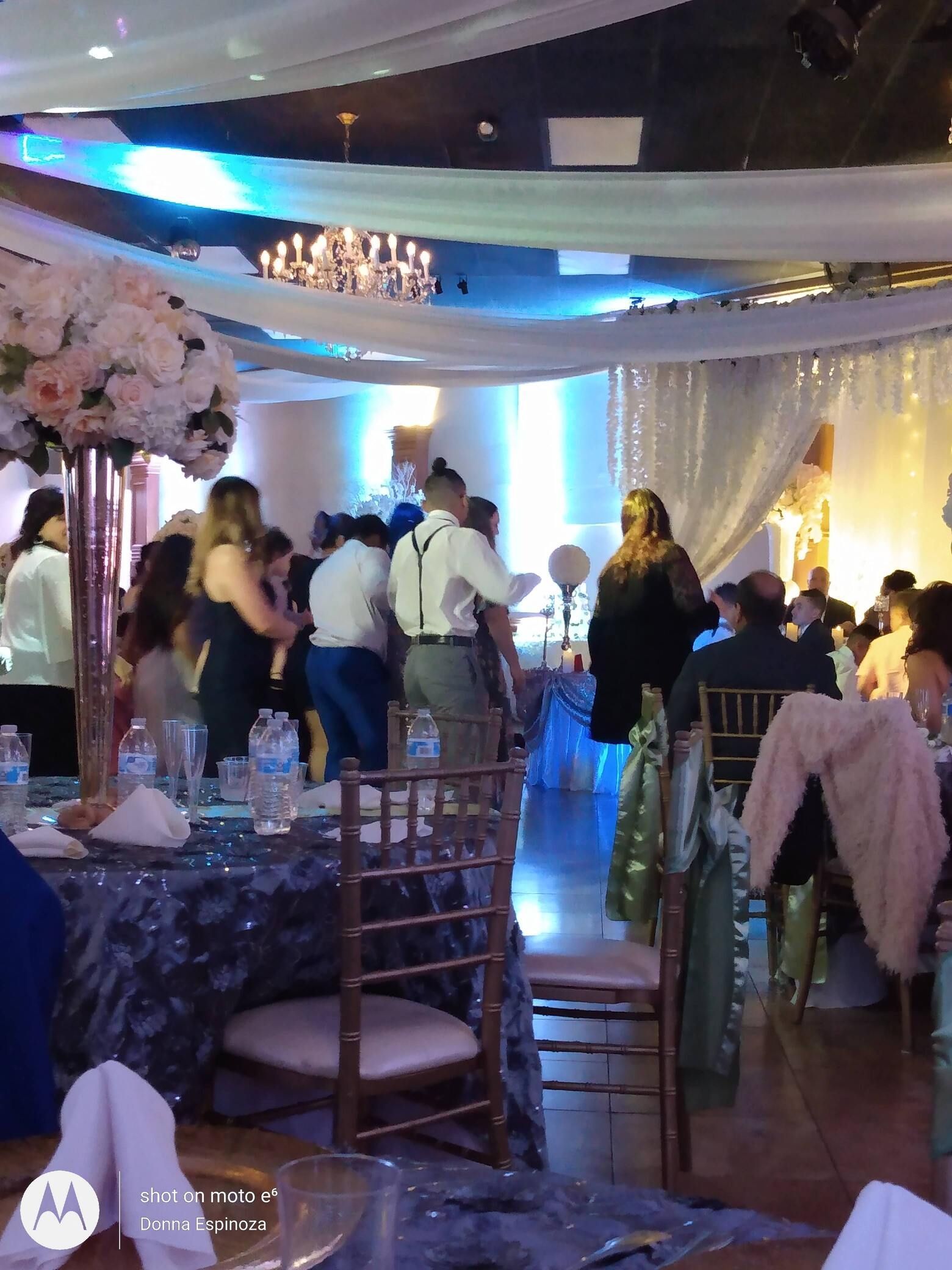 Guests mingling at a decorated indoor reception with blue lighting and draped ceilings