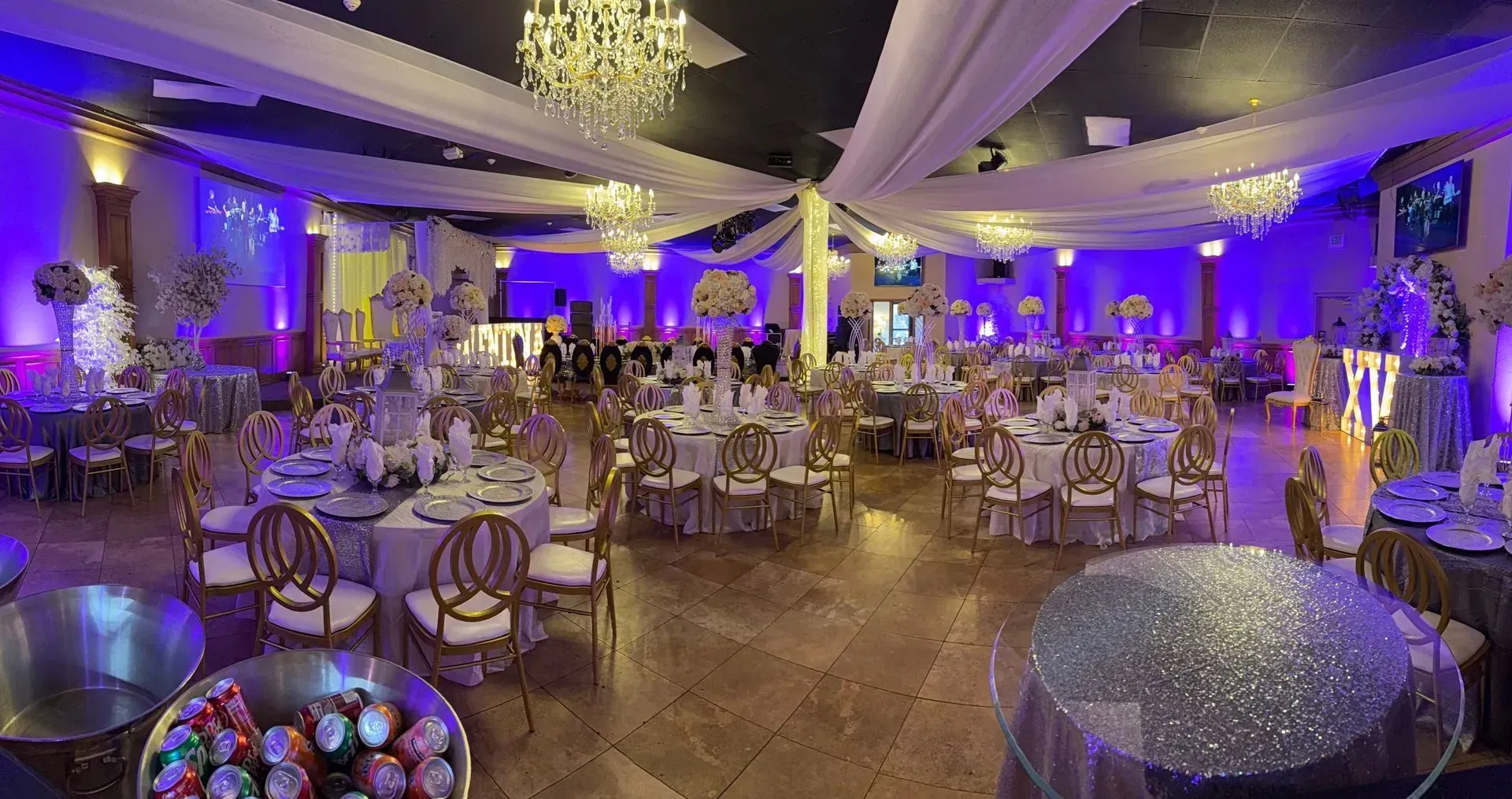 Elegant banquet hall with round tables, white drapery, and purple lighting for a formal event