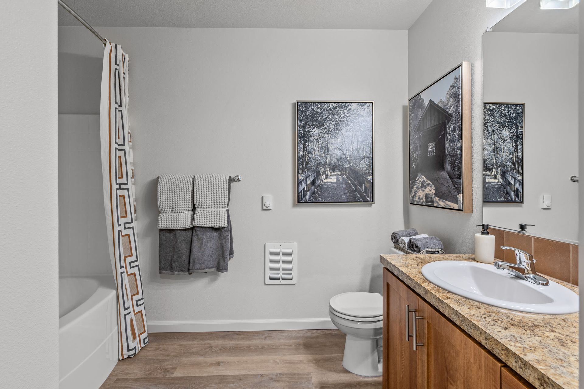 Bathroom in apartment with sink, cabinet, mirror, toilet, towel rack, shower curtain.
