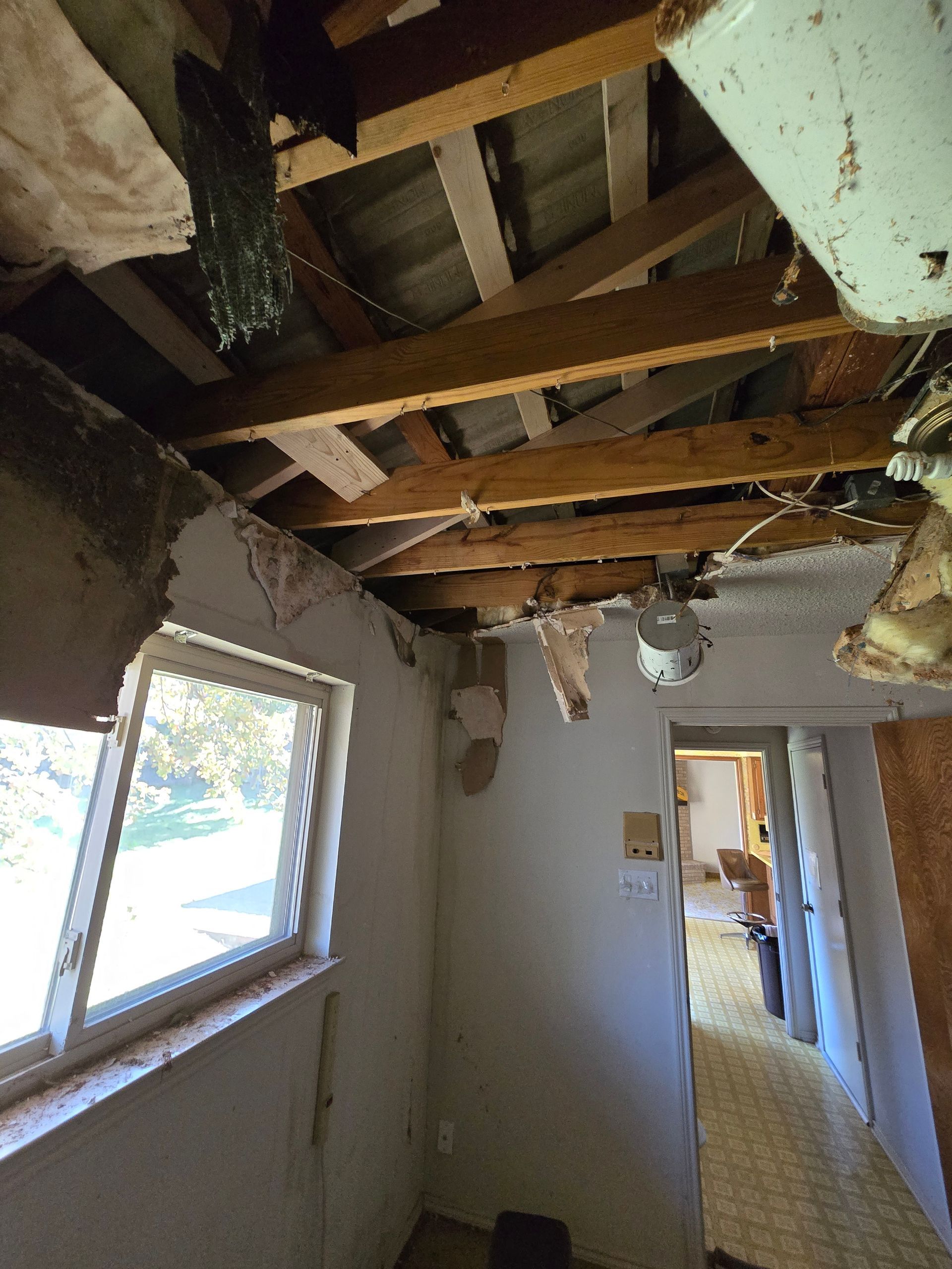 A room with a broken ceiling and a window