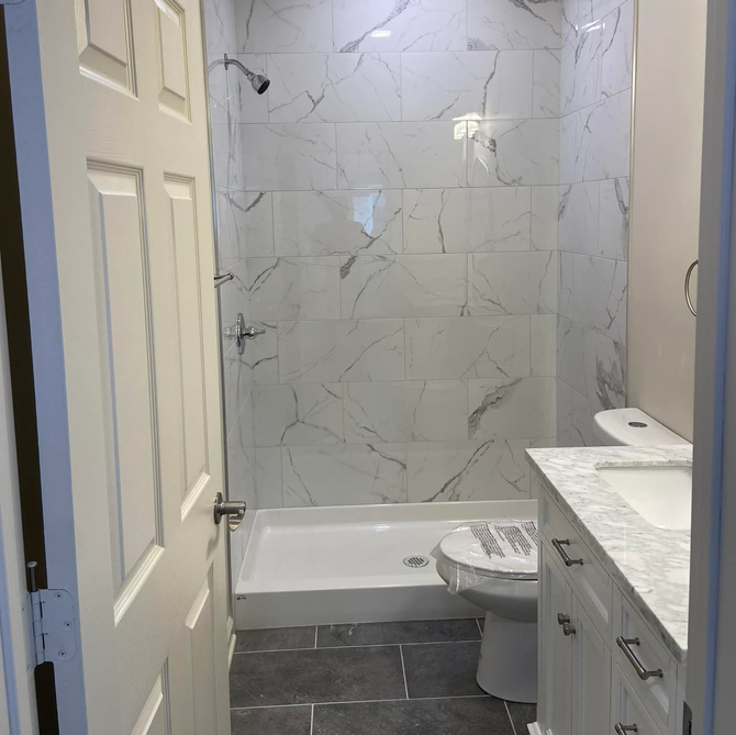 Bathroom with a clawfoot tub, pedestal sink, wooden floors, and skylight. Light and airy.