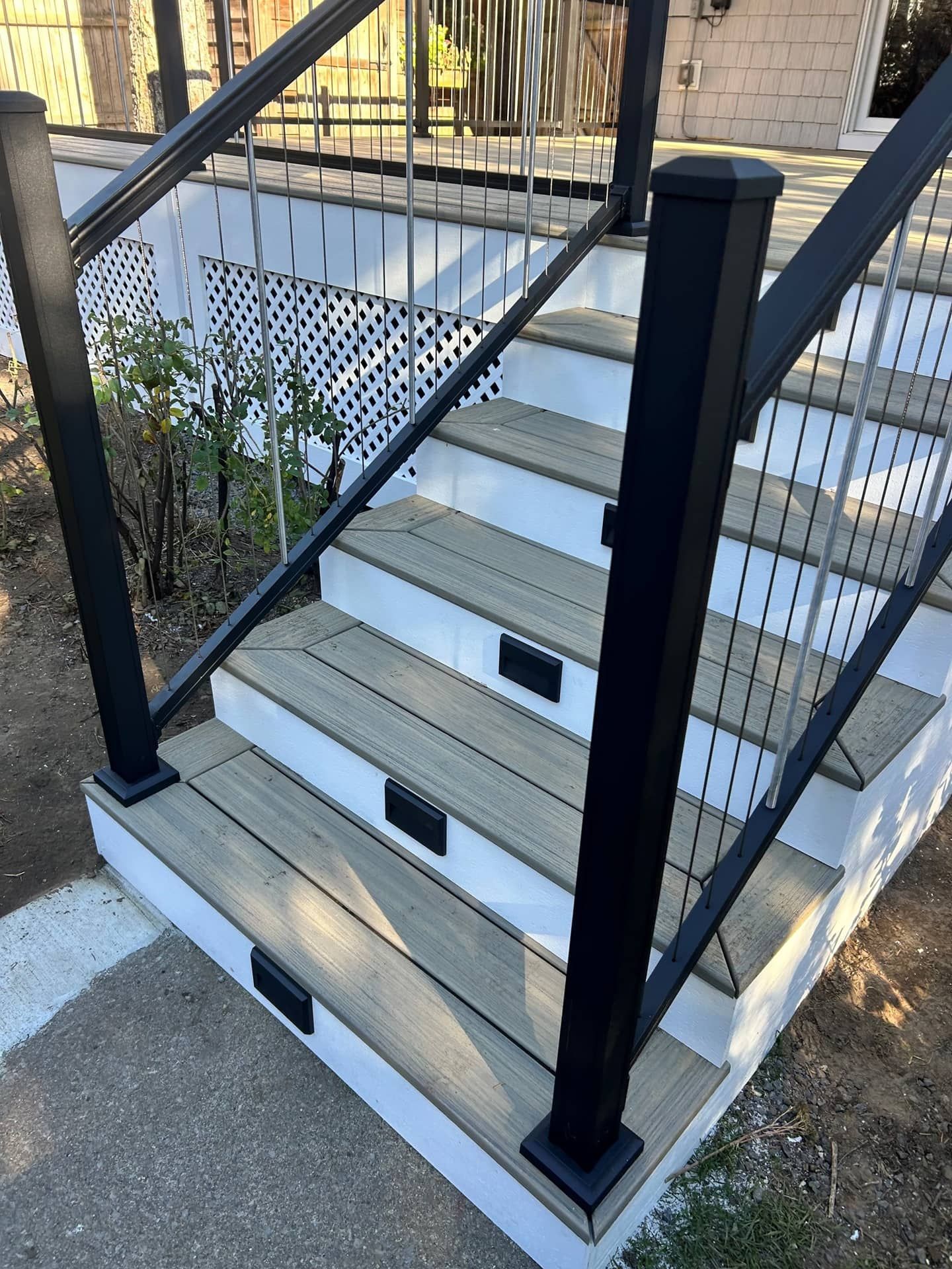 Exterior staircase with white steps, black railings, and black posts beside a building.