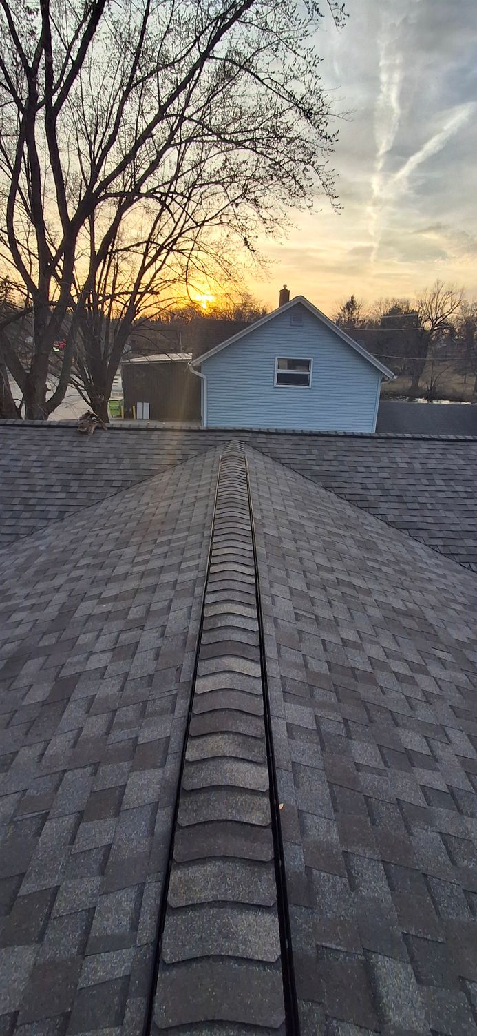 View from a roof showing a house and a sunset. The roof has a center brick pathway.