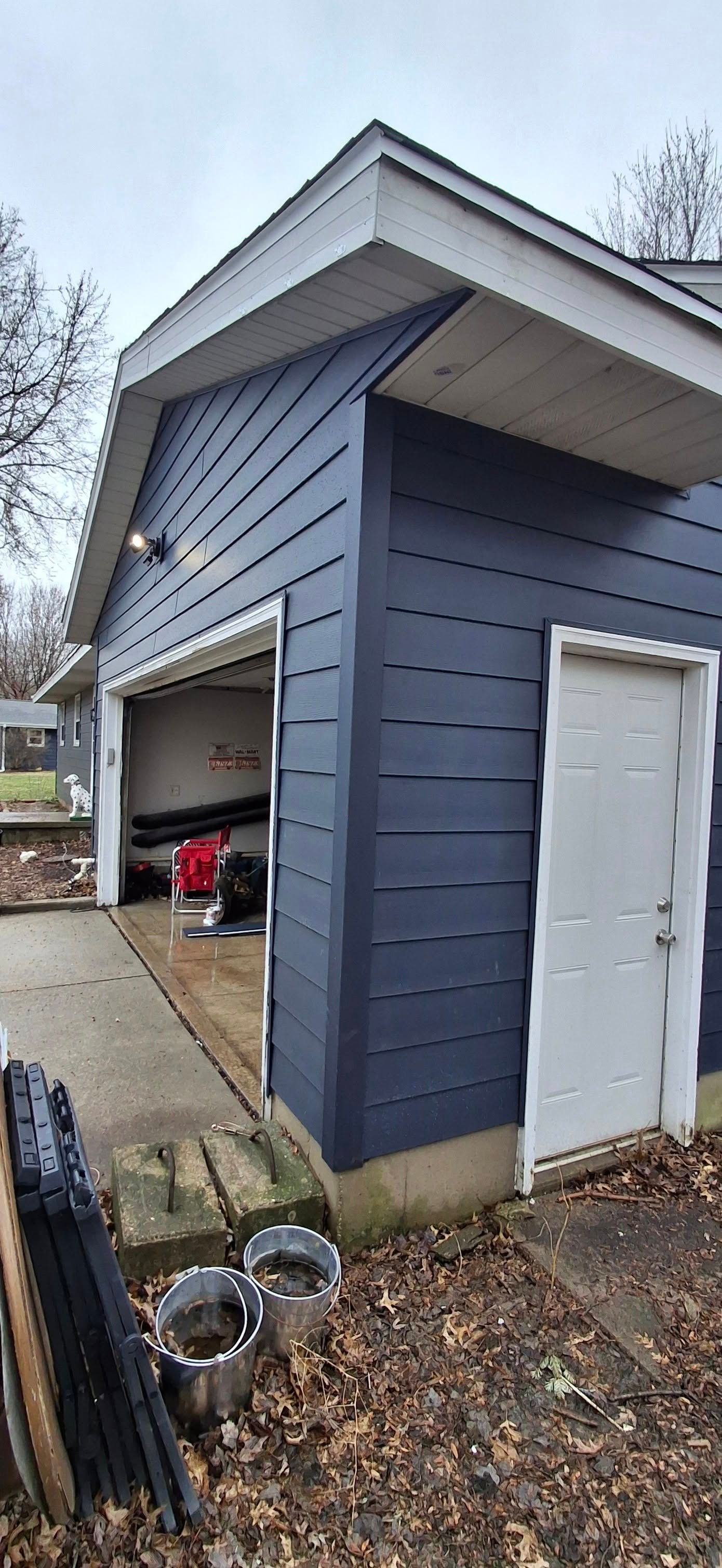 Blue garage with white trim, open garage door, and white side door.