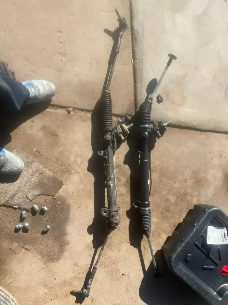 Two black bicycle forks and steering assemblies on concrete near a shoe and a black bag.
