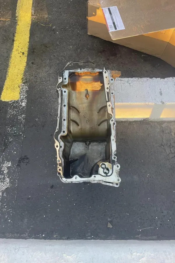 Empty metal engine part on asphalt beside a cardboard box and painted yellow line