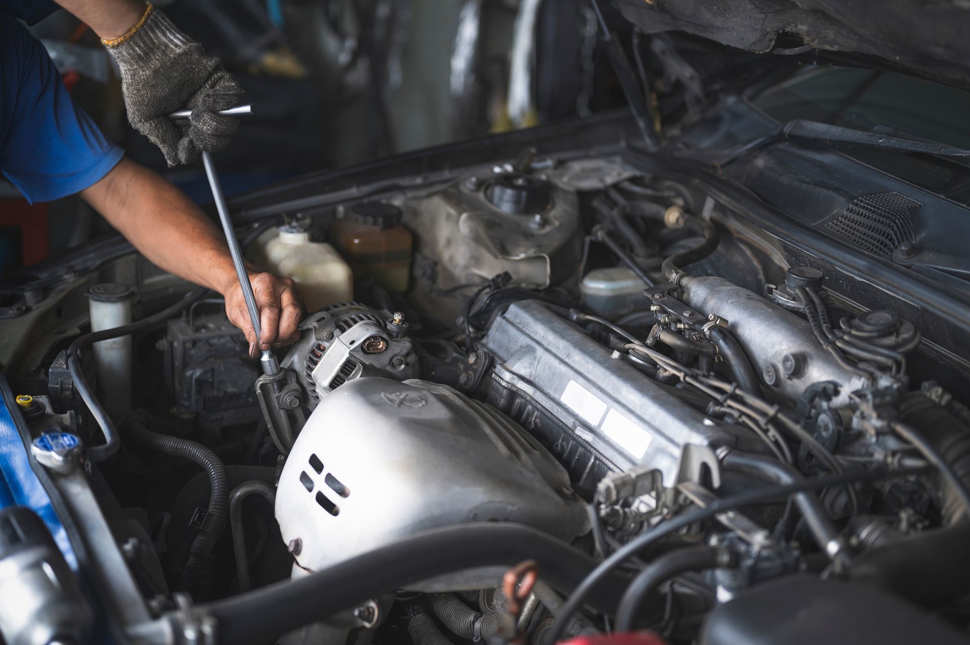 Mechanic using a wrench to work on a car engine under the hood