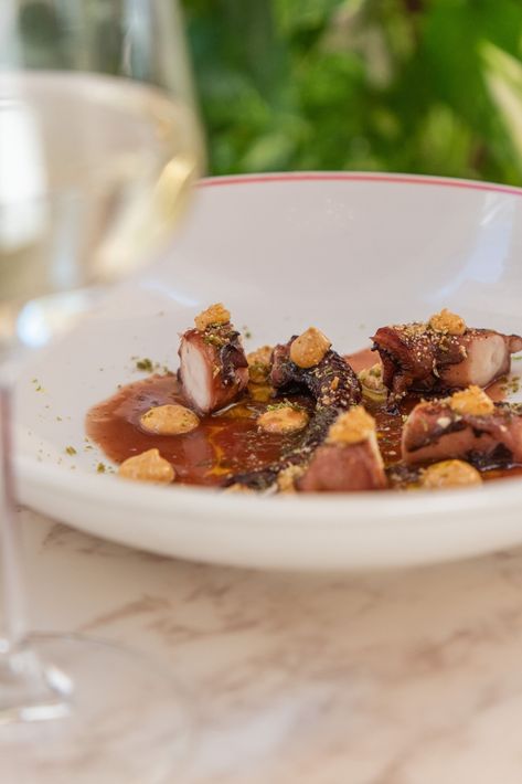 Un petto di pollo affettato con spinaci e salsa rossa su un piatto, con un bicchiere di vino bianco su un tavolino di marmo in un caffè.