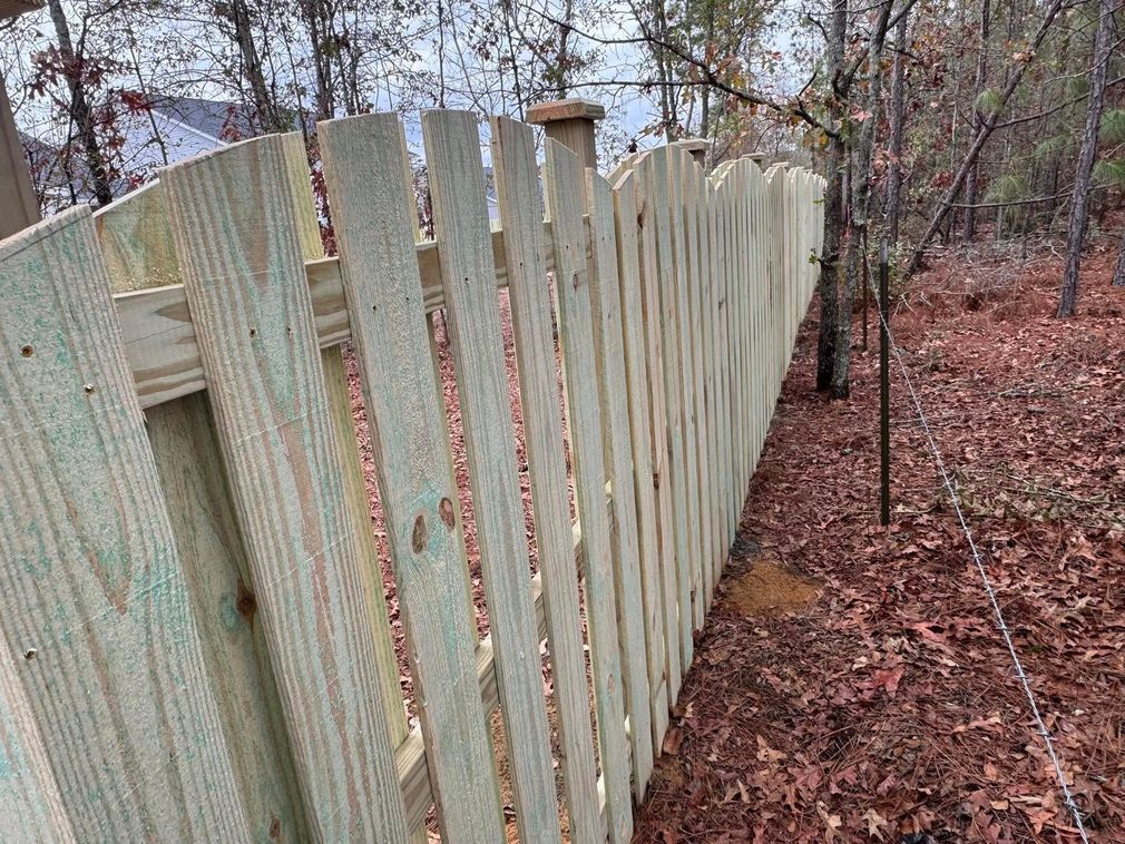 Weathered wooden fence running through a leaf-strewn wooded yard