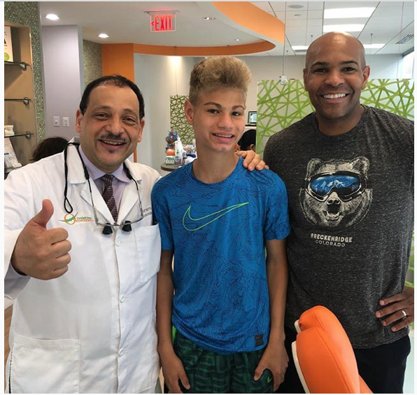 Man with doctor and boy with braces smiling. Dentist's office.