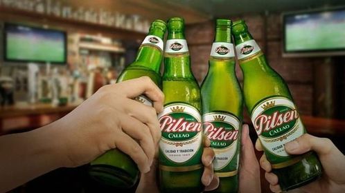 En un bar, las manos chocan entre sí, dando vueltas botellas de cerveza Pilsen verde.