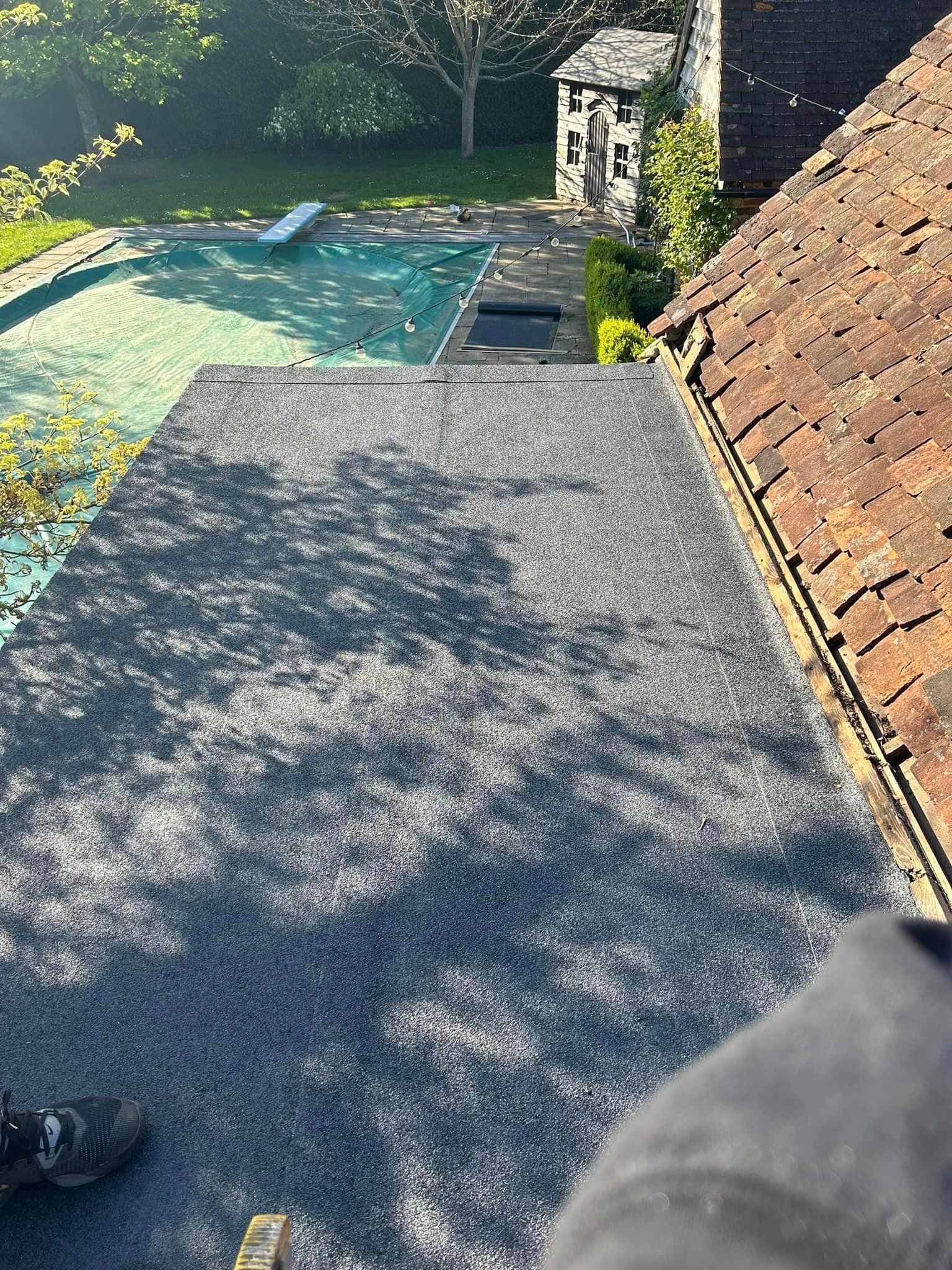 A person is standing on a roof next to a pool.