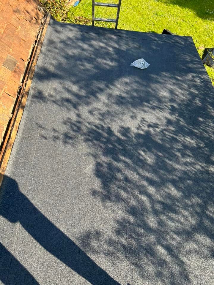 Aflat felt roof with a ladder sitting on top of it.