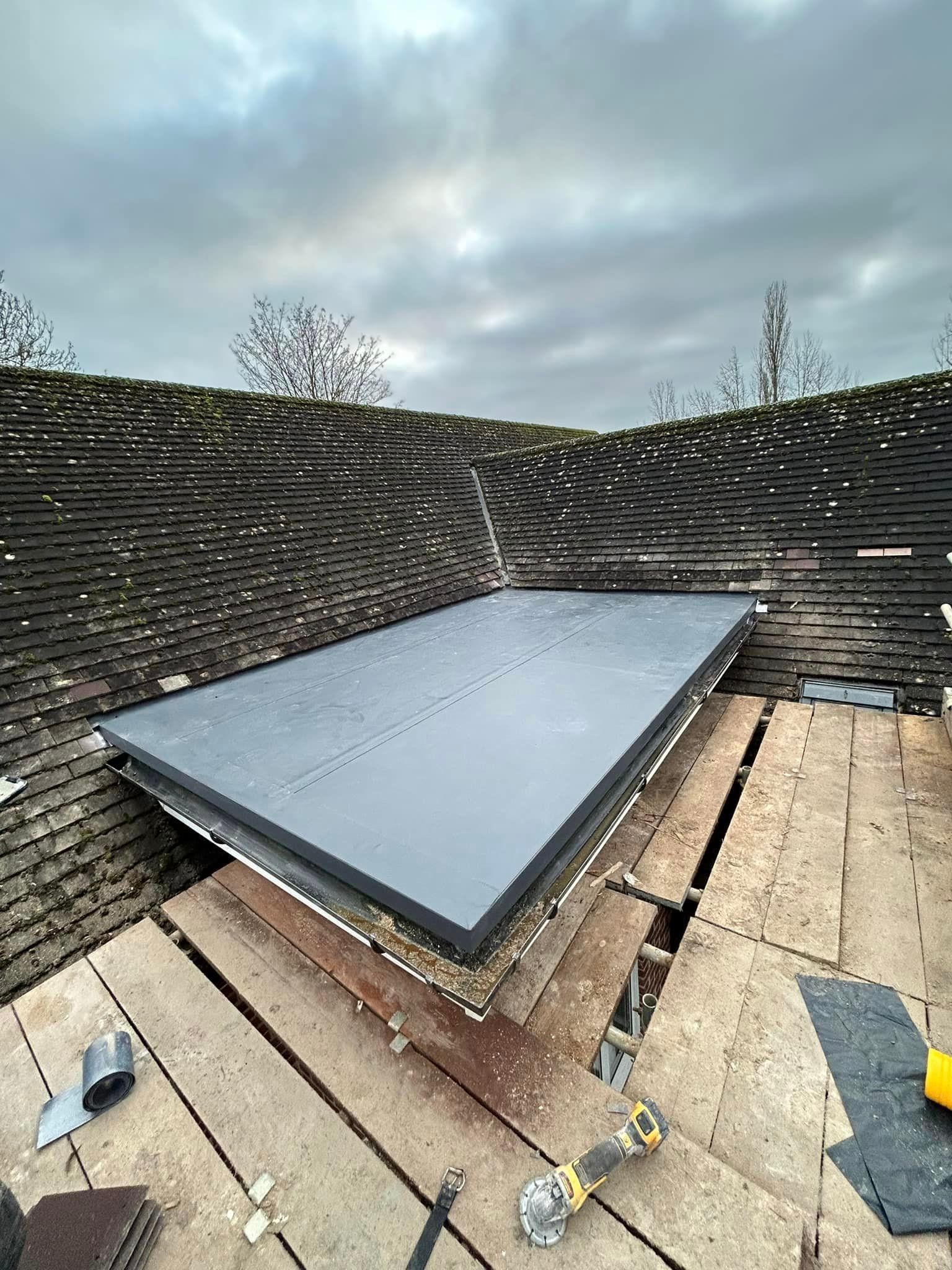 A flat roof being installed next to a tiled roof on a traditional house