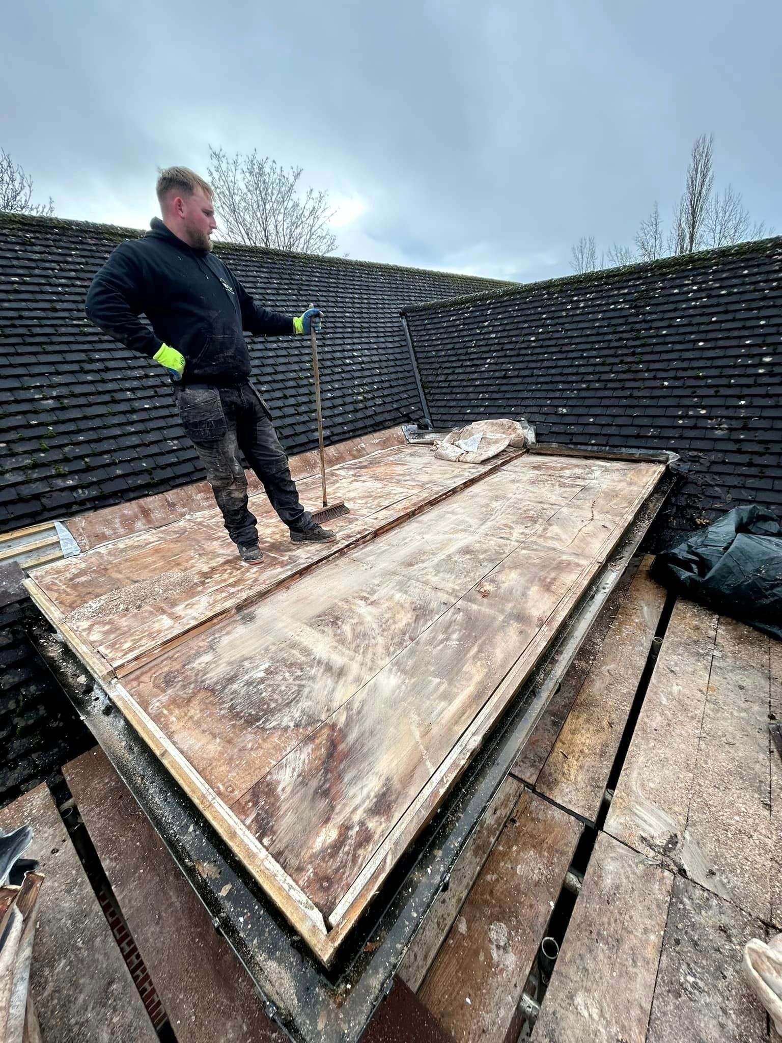 A man is standing on top of a wooden roof.