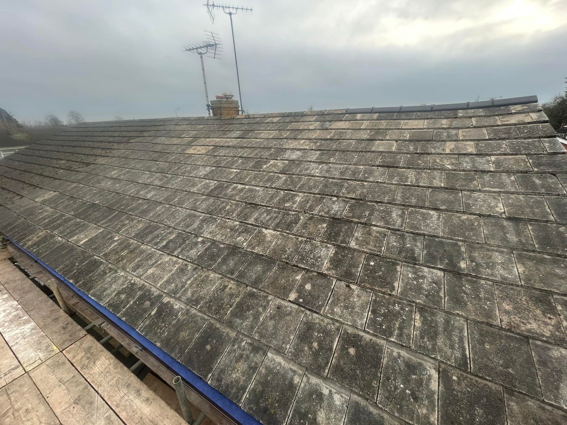 A roof with a lot of tiles on it and a blue gutter.